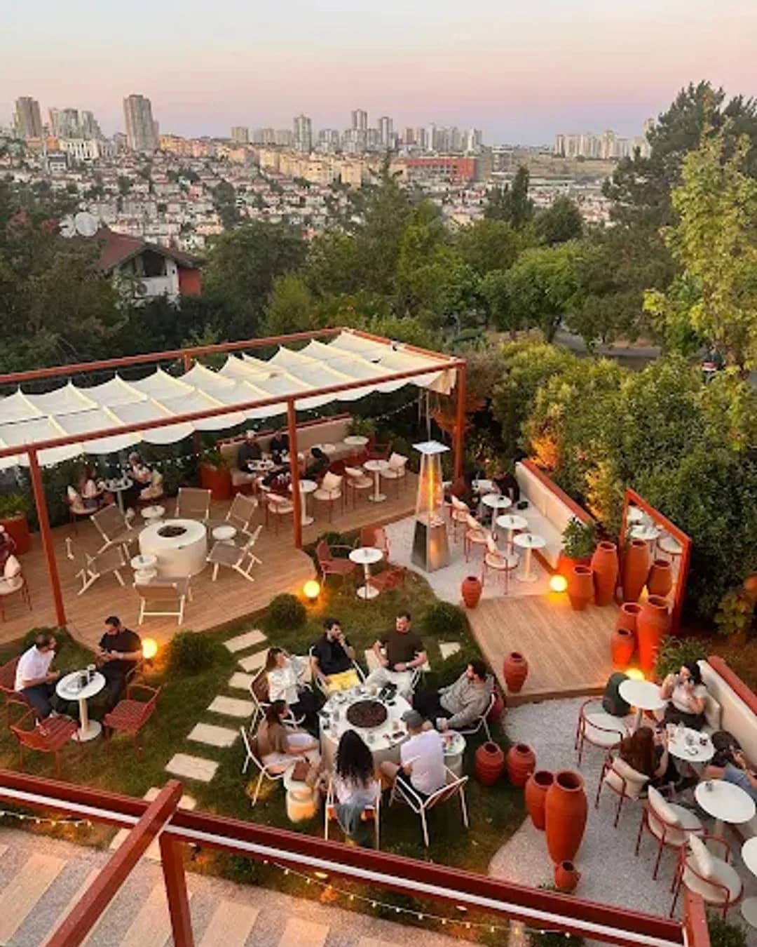 Ruum'un Bahçeşehir'deki terası: beyaz gölgelikler, turuncu pergola ve arkada şehir silüeti